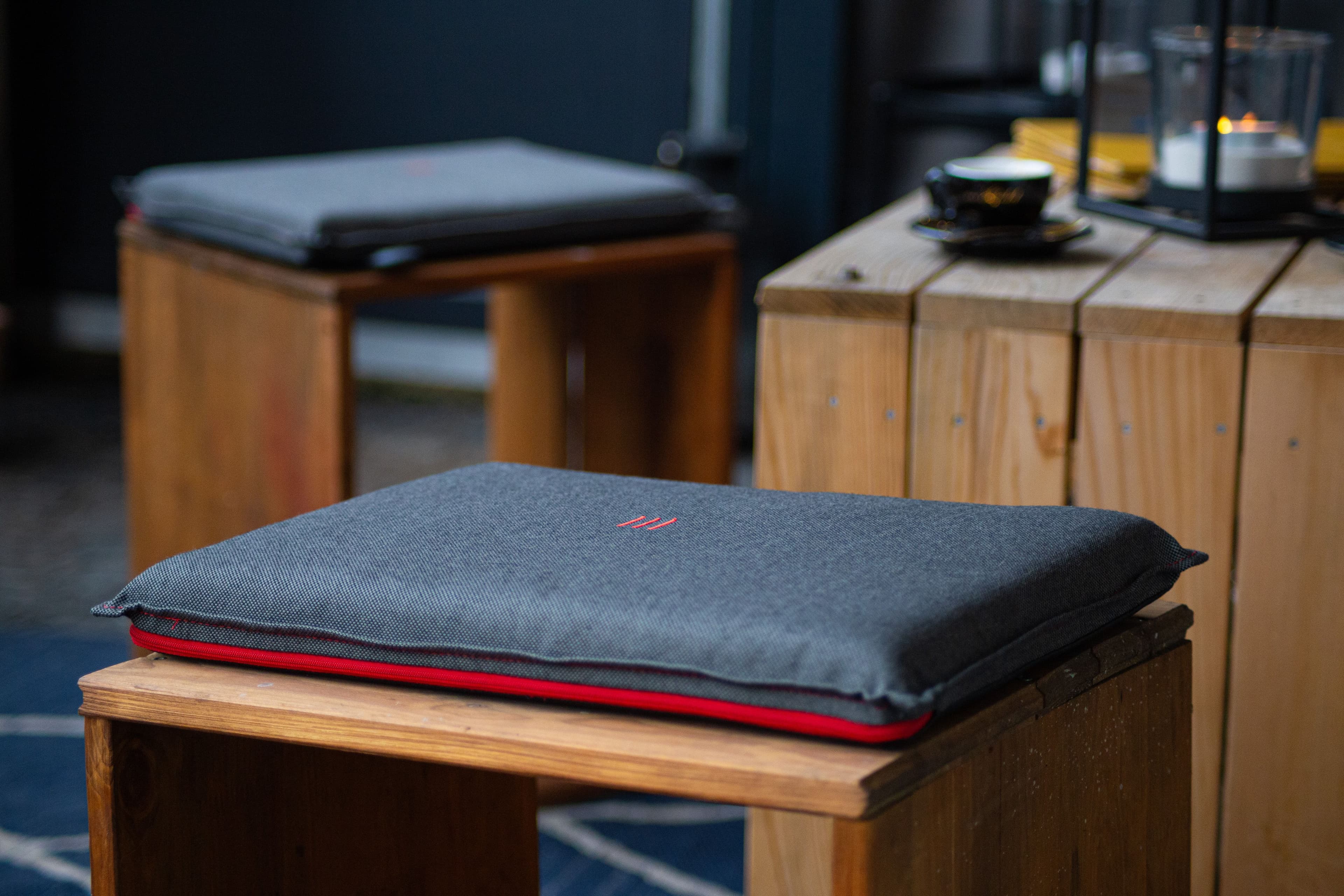 heatme Smart Heizkissen in dunkelgrauem Stoff auf Holzhocker — Nahaufnahme